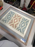 Framed textile pattern art print on table top, showing full front view