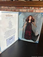 Open display box showing doll in gown and interior text panel