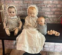 Group shot of all three composition baby dolls and jointed wooden bear on table