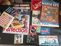 All boxed games, card decks and marbles laid out on table