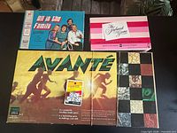 Top view of four game boxes laid flat: All In The Family Game, The Newlywed Game, Avante, small dice game