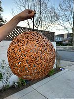 Hand holding wicker globe pendant outdoors