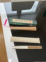 All items laid out: Chinese green case, wooden fan, beige pouch, Japanese fan