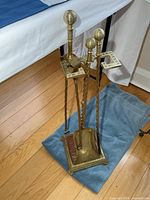 Full view of brass fireplace tool set on stand showing all components