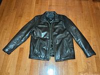 Front view of brown leather coat laid flat