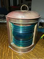 Angled view of brass lantern showing green lens and top handle