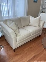Front angled view of Stickley loveseat showing upholstery, pillows, armrest covers, legs