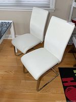 Two white padded Structube chairs with chrome bases