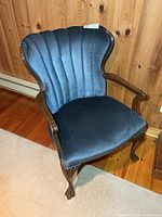 Front view of wood framed armchair with blue velour upholstery
