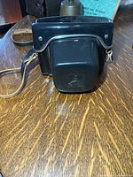 Closed black leather Praktica case front view on table