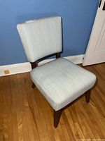 Front view of the armless chair showing upholstery and wood legs