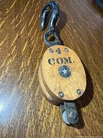 Full view of wooden pulley with metal hook