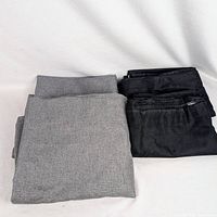 Folded dark gray and black blackout curtain panels displayed on surface