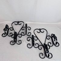Both black wrought iron sconces showing overall design and three candle holders each