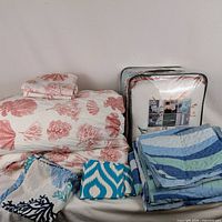 All bedding items grouped: coral print set, blue quilt set, pillow covers, packaged duvet set