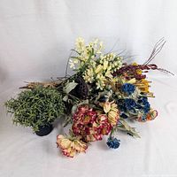 Pile of assorted faux floral bouquets and potted greenery