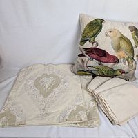 Group shot showing bird pillow, folded velvet covers and linen cloths