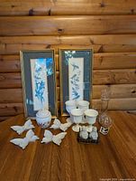 Group shot showing all items on table: jar, plates, goblets, UnCandle, framed prints