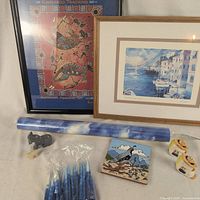 Group view of all items: two framed prints, window film roll, candles, stone donkey figurine, ceramic tile, two tape rolls
