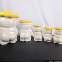 Front view of cookie jar and four matching smaller pieces showing relative sizes and yellow hat lids