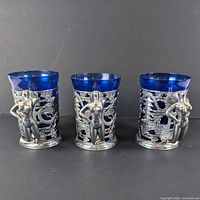 Front view of three cobalt blue glass tankards showing overlay and handles