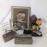 group shot of all items including needlepoint, brass spittoon, tissue box, letter rack, pistol, glass clown, desk tray, stapler, utensils