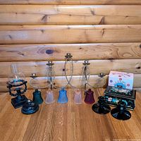 Group view of all items including cast iron holder, brass candelabra, four glass votive shades, two black candlesticks, metal box, fragrance box