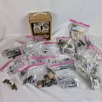 overview showing all zip bags of hinges, knobs, brass pull, boxed handle set