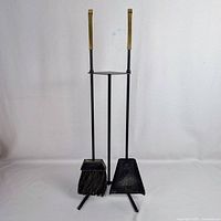 Full view of stand holding broom and dustpan