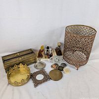 Group shot of all items showing metal tissue box cover, wastebasket, tray, mirror, ring holder, clock, organizer, perfume bottles, compacts
