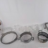 Three glass lids and three round silver-plate holders on display