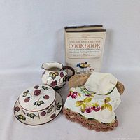 Full lot showing condiment dish with lid, pitcher, cookbook, embroidered linen