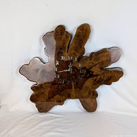 Front view showing wood slab clock face with Roman numerals and hands