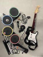 Full lot view: guitar controller, drum pads, foot pedal, stand parts, cables