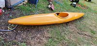 Side profile of yellow racing kayak on ground