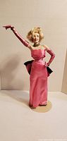 Front view of Marilyn Monroe porcelain doll in pink satin gown on stand