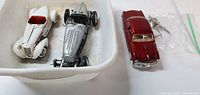 overview of three diecast cars in bin with parts bag