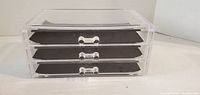 Front view of clear acrylic organizer showing three drawers and pulls