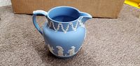 Front view of blue Jasperware pitcher showing white relief