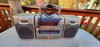 Front view of Aiwa CA-DW24 series boombox with speakers attached and power cord on handle