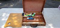 Open wooden artist paint case with palette and supplies displayed