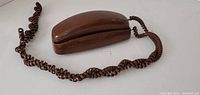 Top view of brown slimline telephone with coiled cord