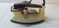 Side view of General Electric yellow steam iron showing body, handle, dial, and controls