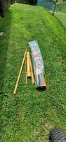 Umbrella components on grass: bamboo pole, base, folded canopy
