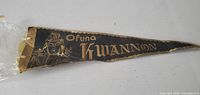 Front of black felt pennant showing gold text and Kannon image
