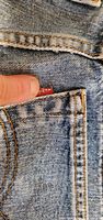 Close-up of red Levi's tab on pocket, showing brand identifier and fabric texture
