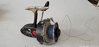 Left side view of Mitchell Garcia 302 reel showing body, spool with blue line and bail wire