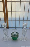 Front view of two crystal candlesticks and one green votive