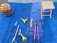 All items laid out on blue blanket: plant hangers, tools, stool, bucket, trivet