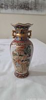 Front view of porcelain vase showing hand-painted figural scene and gilt accents